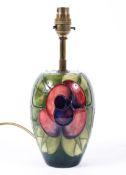 A Moorcroft table lamp decorated with a scrolled red flower on a green ground 43cm high.