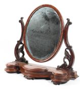 A Victorian mahogany oval swing mirror flanked by acanthus supports above three lidded compartments