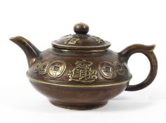 A small Chinese bronze teapot decorated in relief to the lid and body with Chinese characters and