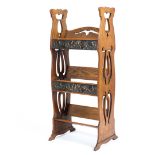 An Art Nouveau freestanding oak bookcase of small proportions with two copper hand beaten plates in