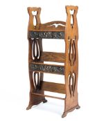 An Art Nouveau freestanding oak bookcase of small proportions with two copper hand beaten plates in