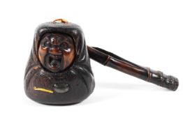 A 19th century Japanese smoking set comprising a boxwood tonkotsu carved as a daruma strung