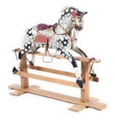 A wooden dapple grey rocking horse complete with bridal and stirrups mounted on a wooden sliding