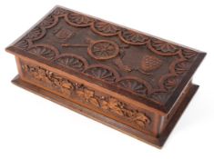 An Oak WW1 lidded box with all over carved decoration with central cannon and two shields to the