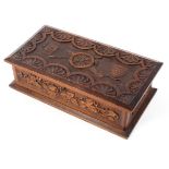 An Oak WW1 lidded box with all over carved decoration with central cannon and two shields to the