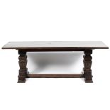 An oak refectory table with heavily carved square supports united by a stretcher,