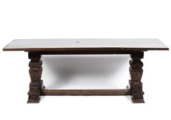 An oak refectory table with heavily carved square supports united by a stretcher,