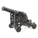 A cast iron garden table top cannon with pierced sides mounted on a set of four wheels,