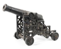 A cast iron garden table top cannon with pierced sides mounted on a set of four wheels,