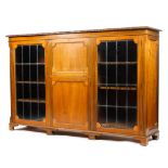 An Edwardian walnut sideboard with carved frieze above a central fall front and cupboard flanked by