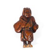 A Meiji dynasty wood netsuke of a standing man with a bandage around his head,