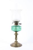 An Edwardian brass mounted oil lamp, with etched clear flared shade and green glass resevoir,