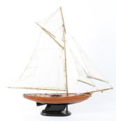 A model of a wooden hulled pond yatch under full sail outer and inner jib mainsail and mainstay