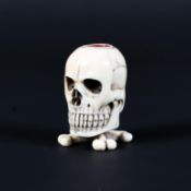 A carved ivory skull shaped match holder/striker, the skull supported on cross bones, 5.