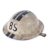 A military helmet, painted in white and marked "BS" and striped in black,