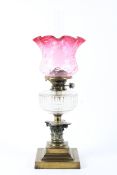 An Edwardian brass mounted oil lamp, with frilled cranberry glass shade, with Hicks Duplex No.