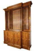 A large Arts and Crafts breakfront bookcase with open shelves above a cuboard base with carved