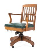 An Arts & Crafts oak captain's swivel desk chair with leather overstuffed seat raised on a