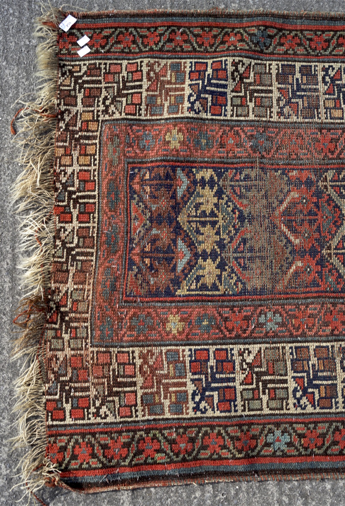 A 20th century woollen woven ground rug, decorated with geometric patterns on a red ground, - Image 2 of 3