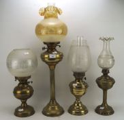 Four late 19th/early 20th century brass oil lamps, each with brass reservoirs and glass shade,