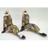 A pair of Italian ceramic figures of harlequins, in seated poses,