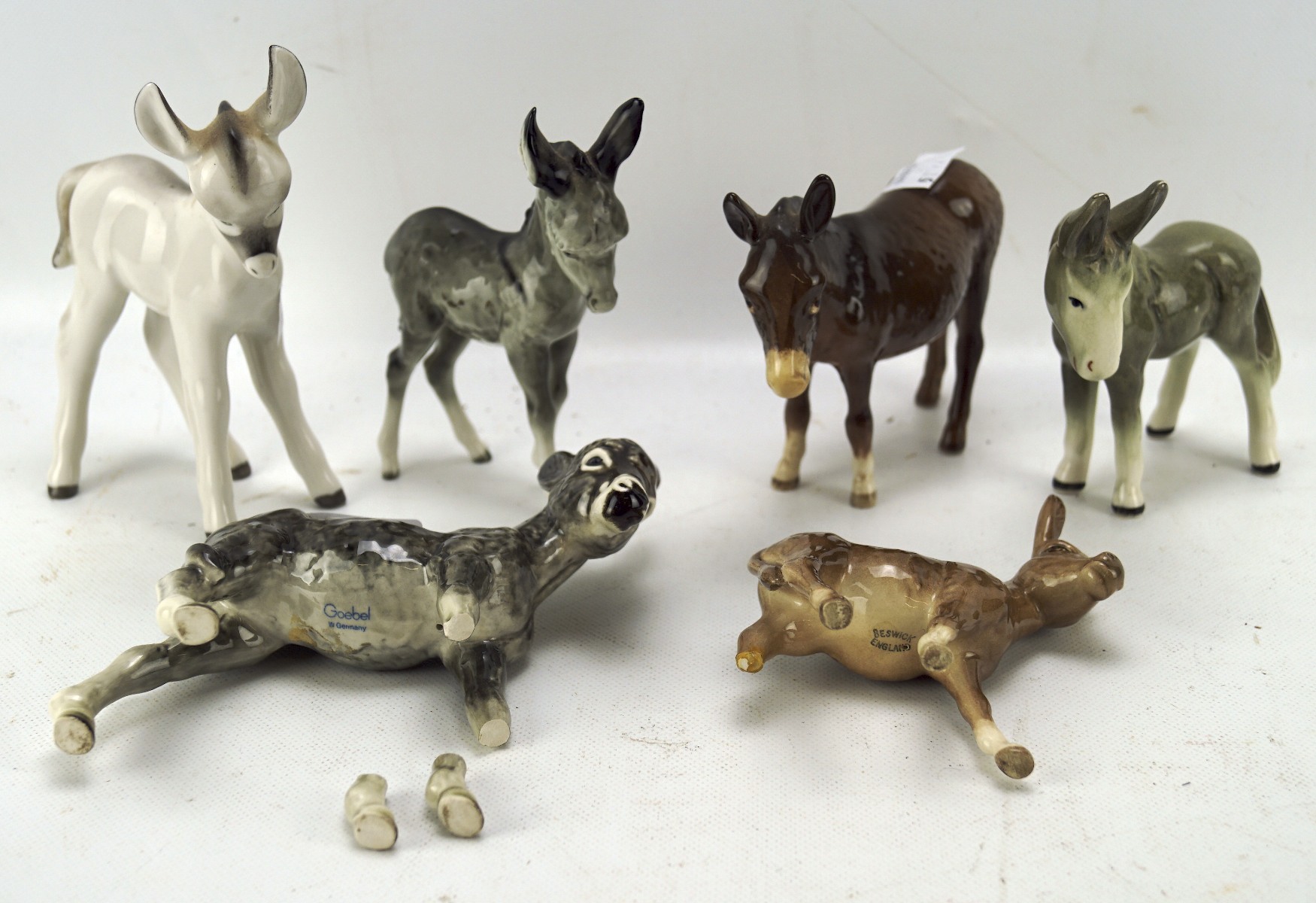 A collection of Beswick donkeys, together with one Goebel example