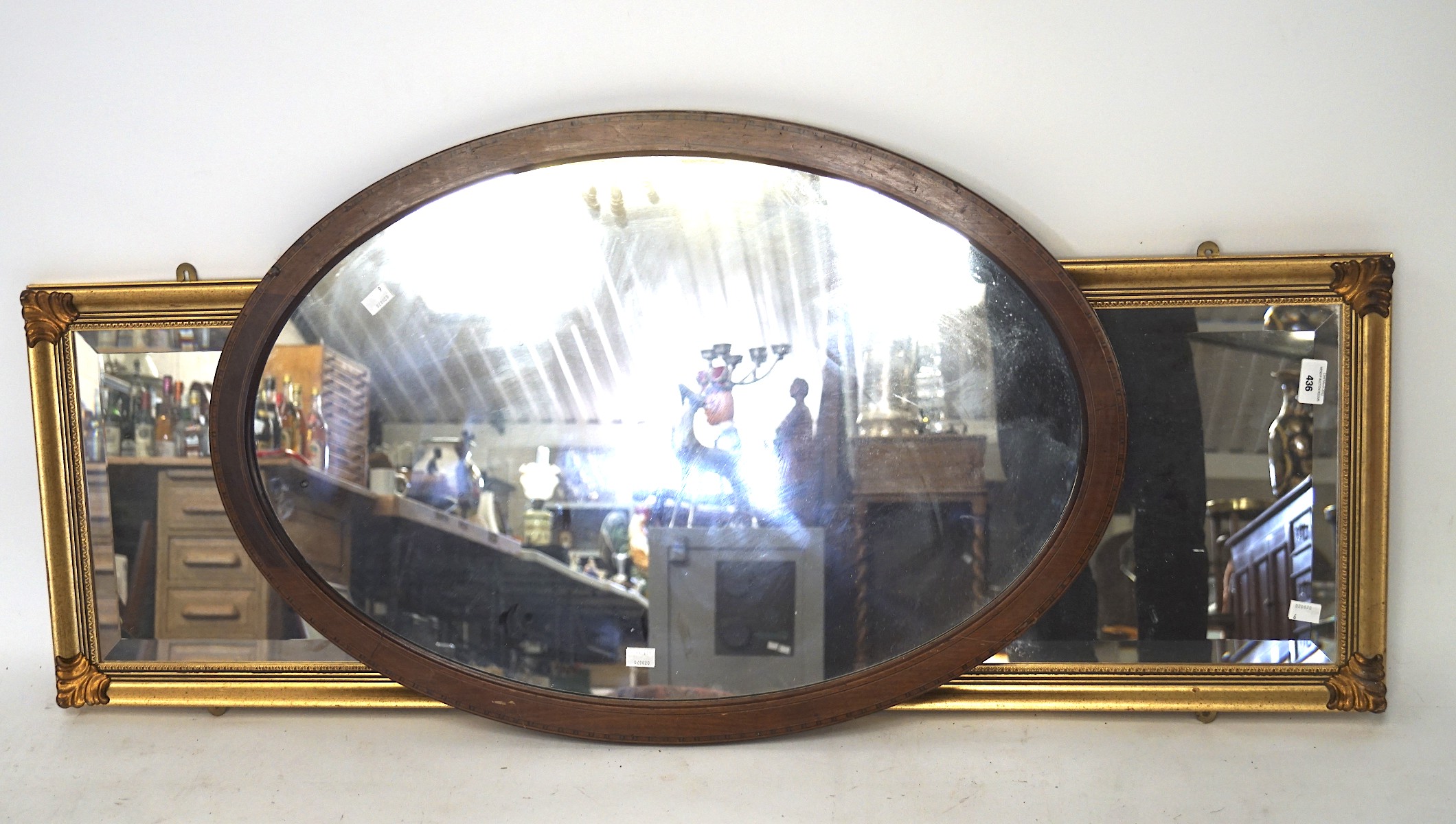 A 19th century oval mirror with inlaid banding and a contemporary rectangular gilt example,