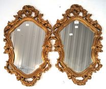 A pair of gilt framed wall mirrors, each with pierced and scrolling motifs to the border,