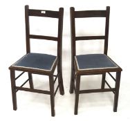 A pair of dark stained wood kitchen chairs with blue upholstered seats,