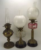 A group of three late 19th/early 20th century brass oil lamps, two having clear glass reservoirs,