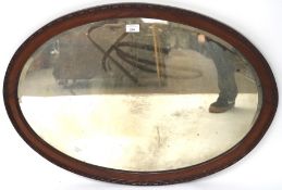 A 20th century bevelled edge over mantle mirror, of oval form, with a wooden frame,