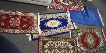 Six small modern rugs with floral and geometric patterns on red, blue and beige grounds,