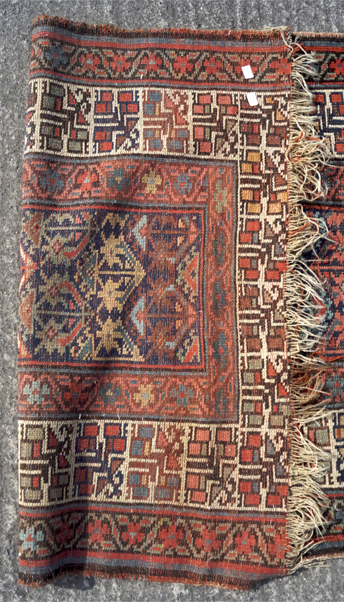 A 20th century woollen woven ground rug, decorated with geometric patterns on a red ground, - Image 3 of 3