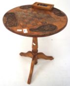 A small round oak side table carved to the top with a draughtsboard surrounded by four oak leaves,