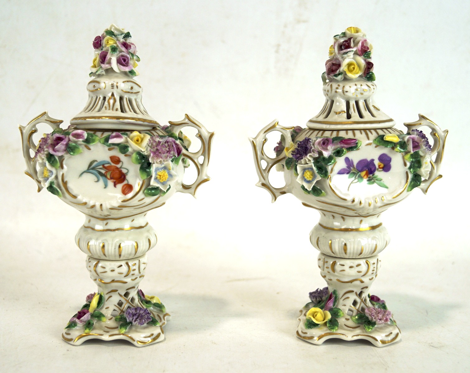 A pair of German porcelain lidded urns, each with twin handles,