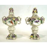 A pair of German porcelain lidded urns, each with twin handles,