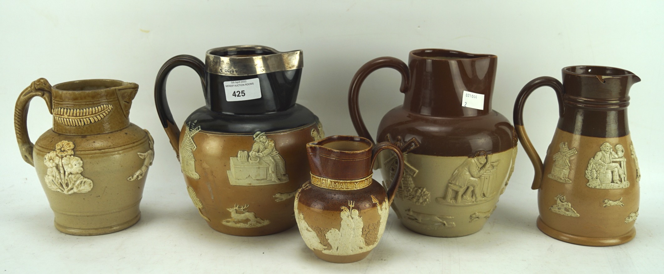 Three Royal Doulton/Lambeth stoneware jugs and two similar, including one silver rimmed example,