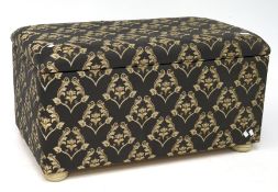 A contemporary ottoman upholstered in gold and black,