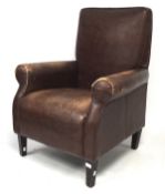 A contemporary armchair, with brown leather upholstery, raised on wooden supports,