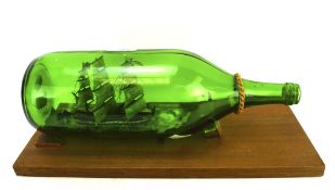 A green glass bottle containing a model of a ship,