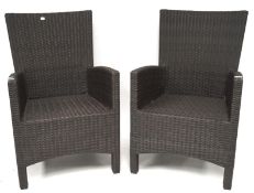 Two dark brown rattan garden armchairs,