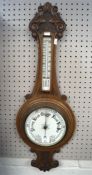 A carved oak wall aneroid barometer and thermometer, with carved scrolling decoration,