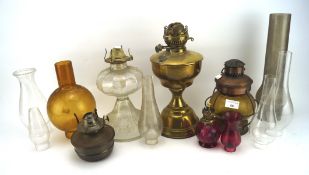 Two antique brass oil lamps and a collection of glass reservoirs and funnels,