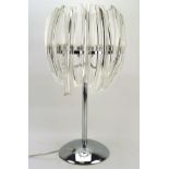 A contemporary glass and chrome table lamp, mounted on a circular base,