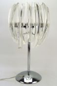 A contemporary glass and chrome table lamp, mounted on a circular base,