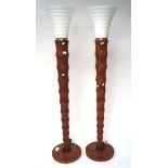 A pair of large contemporary floor lamps, the wooden frames on circular bases, with glass shades,