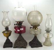 A selection of four late 19th/early 20th century oil lamps, one with cranberry glass reservoir,