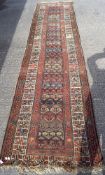 A 20th century woollen woven ground rug, decorated with geometric patterns on a red ground,