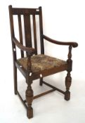 An early 20th century carver chair, the oak frame with carved details, raised on turned supports,