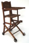 A vintage oak folding child's high chair, on original metal castors,